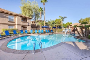 A swimming pool with lounge chairs and palm trees. - Las Vegas | Group Vegas Retreat | Pool + Hot Tub | 2BR (Las Vegas)