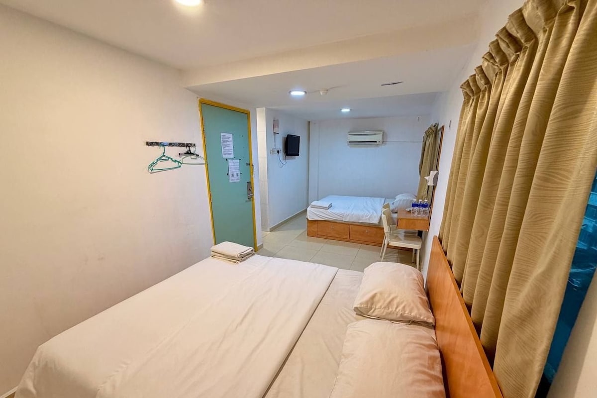 A hotel room with a bed, a bedside table, a chair, and a view of the hallway.
