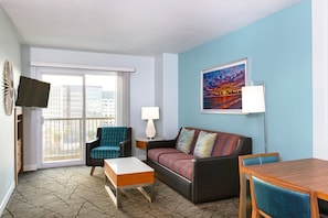 Ein Hotelzimmer mit einer Couch, einem Sessel, einem Couchtisch und einem Esstisch.