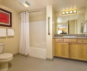 Un bagno con WC, doccia, mobile lavabo con specchio e portasciugamani.
