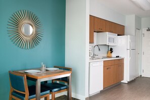 A modern kitchen with white appliances, wooden cabinets, and a teal wall. - Anaheim | Theme Park Weekend Escape | Pool & Hot Tub (Anaheim)