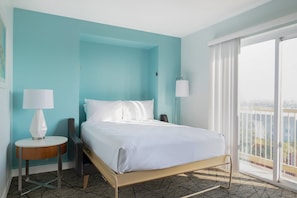 Una camera d'albergo con un letto, due abat-jour, un tavolino e vista all'esterno.