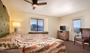 Ein Hotelzimmer mit Bett, Fernseher, Sessel, Fenster und Tür.
