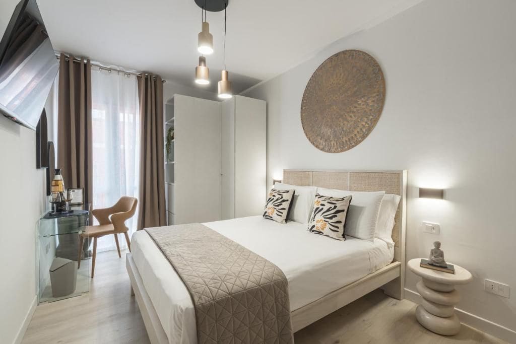Un dormitorio moderno con una cama grande, lámparas de noche, un escritorio con silla y un adorno circular en la pared.