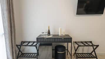 Una habitación moderna con una mesa negra, dos sillas negras, un bote de basura negro y un televisor montado en la pared.