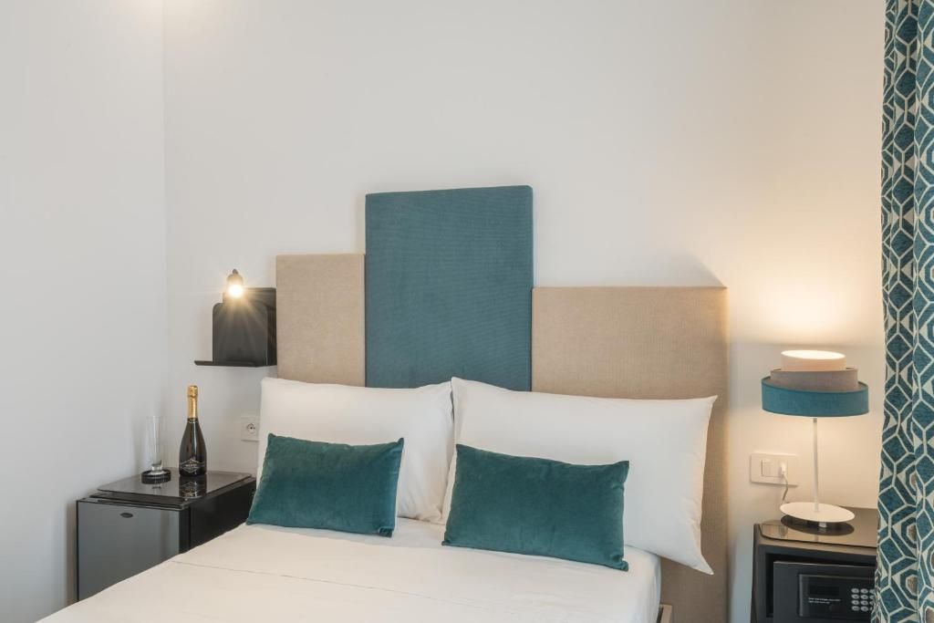 Una habitación de hotel con una cama, mesitas de noche, una lámpara y una estantería en la pared.