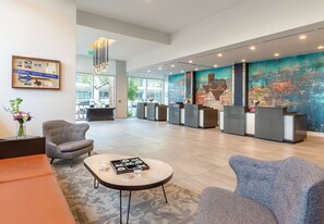 Een ruime lobby met een receptiebalie, een zithoek en een groot abstract kunstwerk.