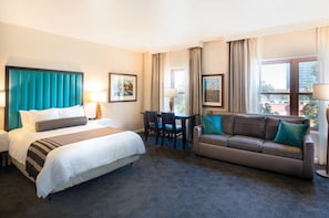 Une chambre d’hôtel avec un lit, un canapé, un bureau et deux chaises.