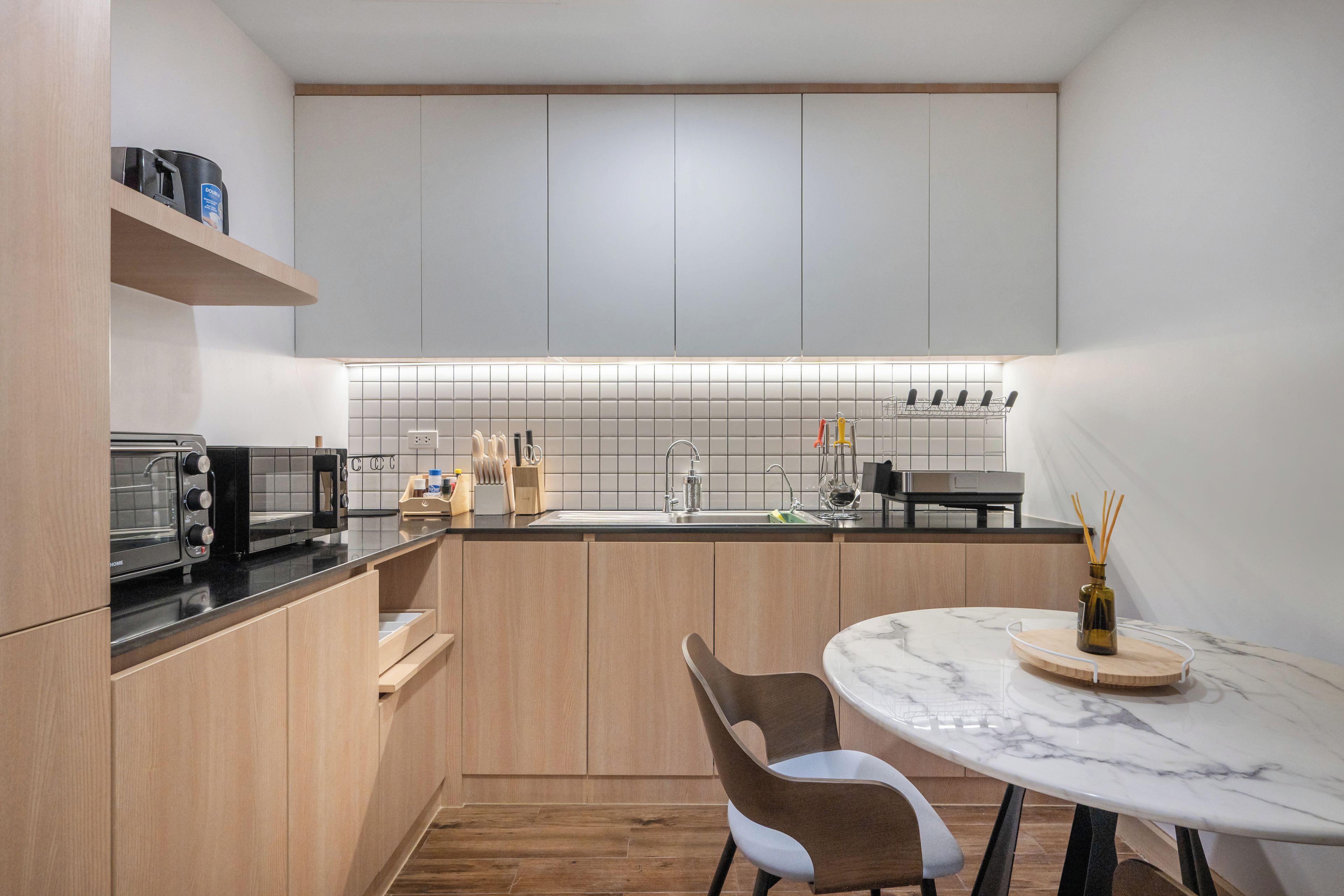 Una cocina moderna con horno empotrado, un fregadero y una zona de comedor con mesa de mármol.