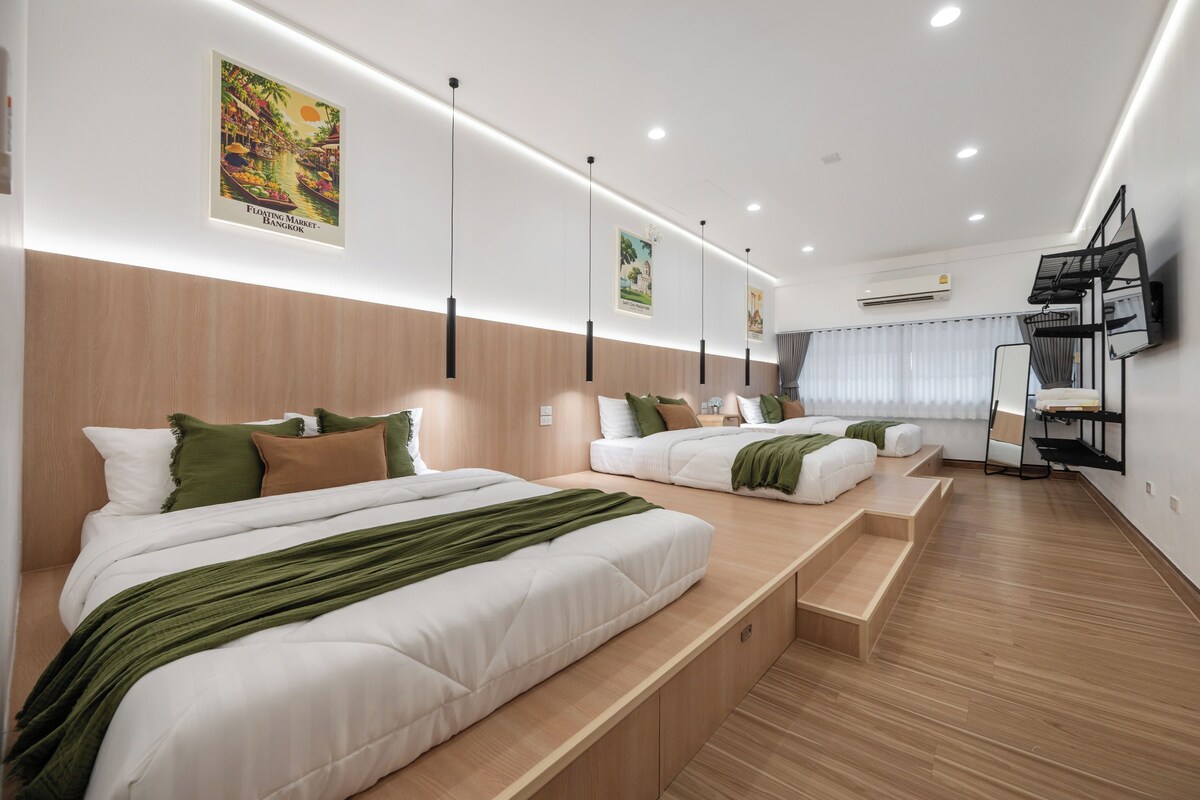 Habitación de hotel con dos camas, zona de estar, televisor de pantalla plana y obras de arte en las paredes.