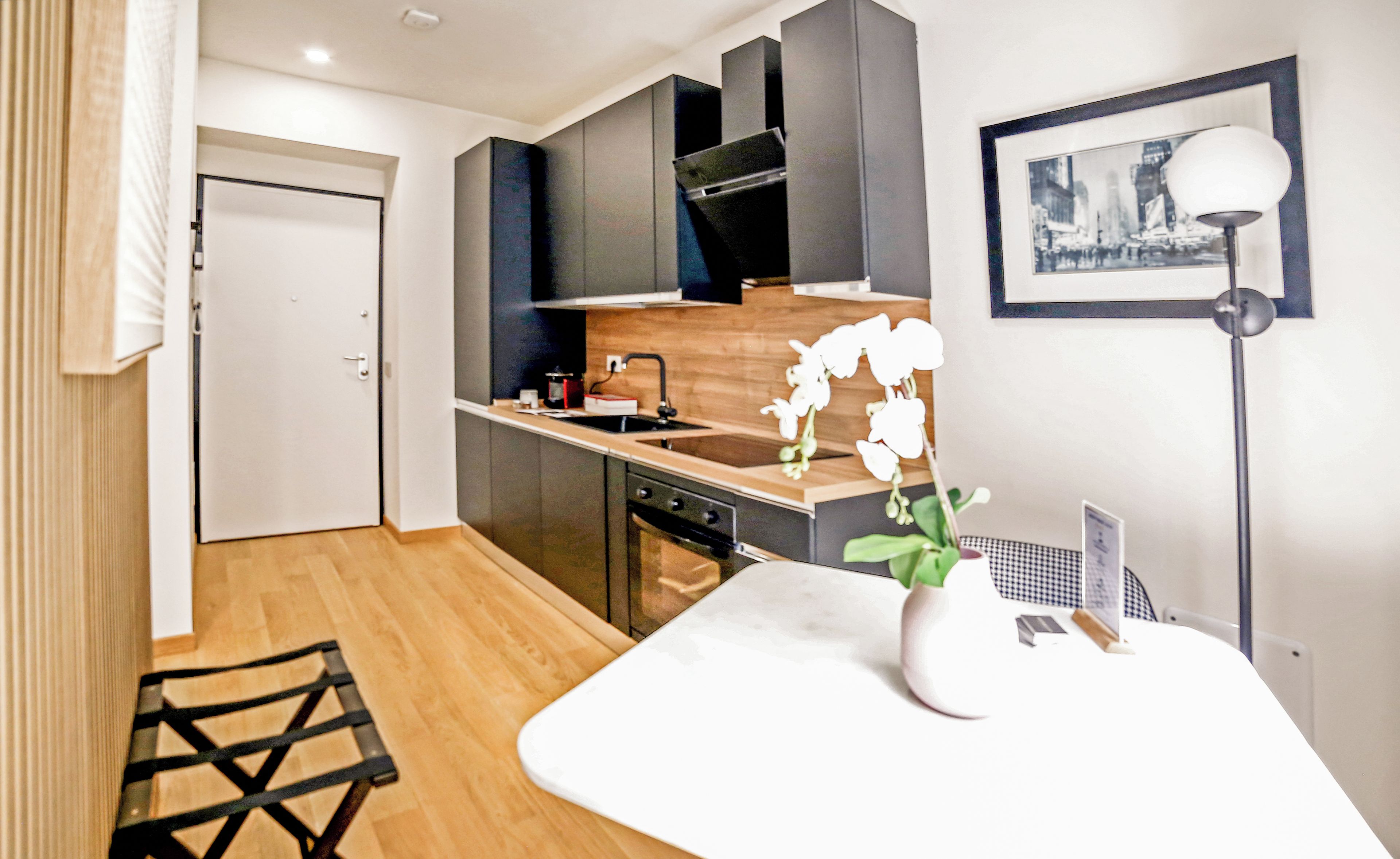 A modern kitchen with a wooden countertop, a sink, and a stove. There is a white orchid on the countertop.