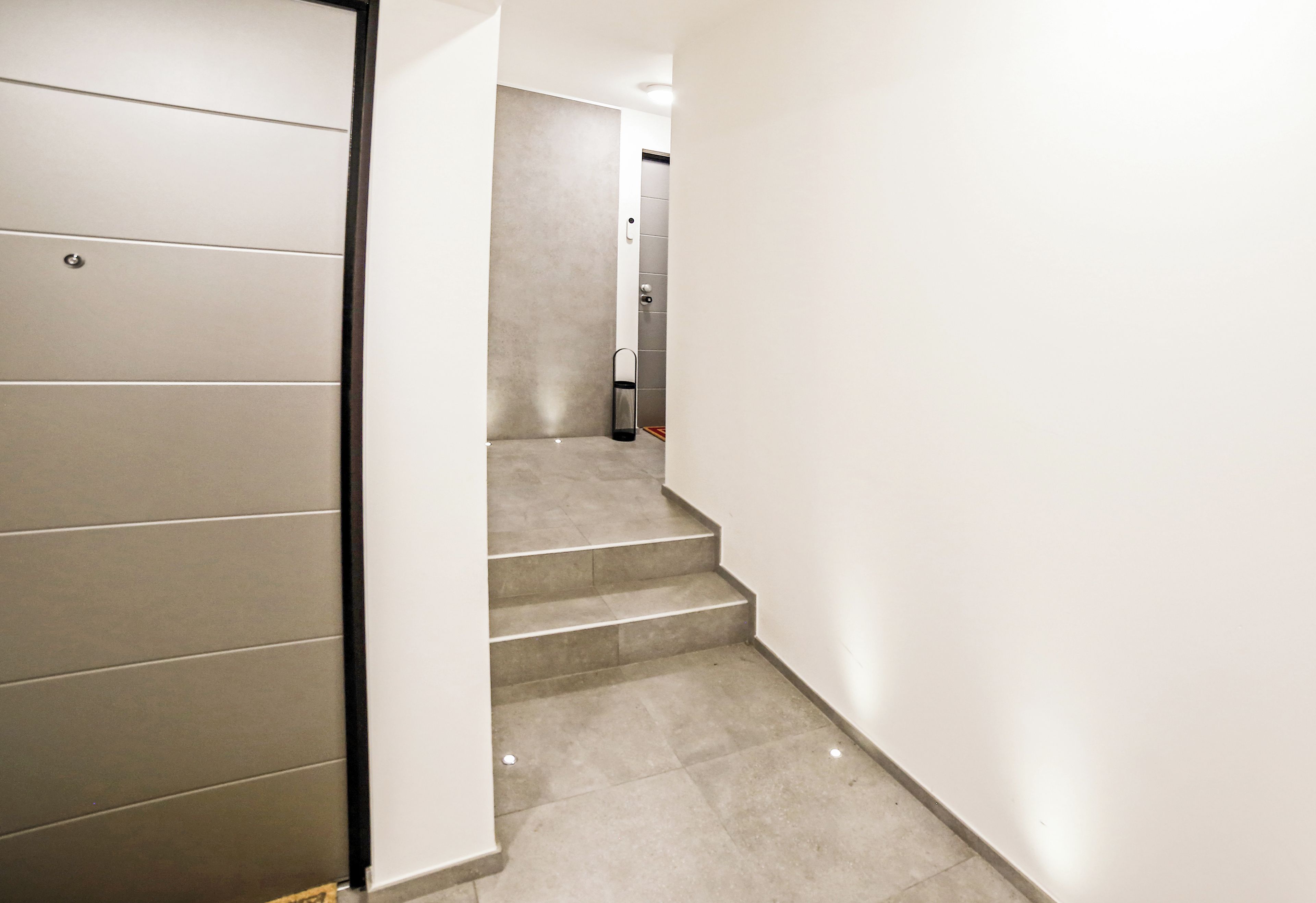 A modern interior with a staircase leading to a room with a door.