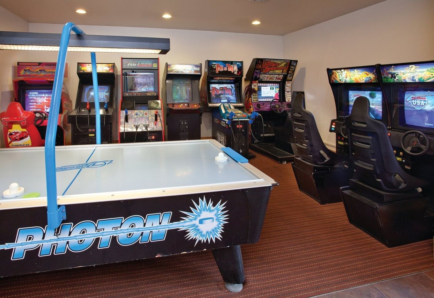 A room with a pool table, arcade games, and a seating area.