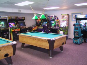 A pool table in a room with arcade games and a sign indicating the area is out of order.