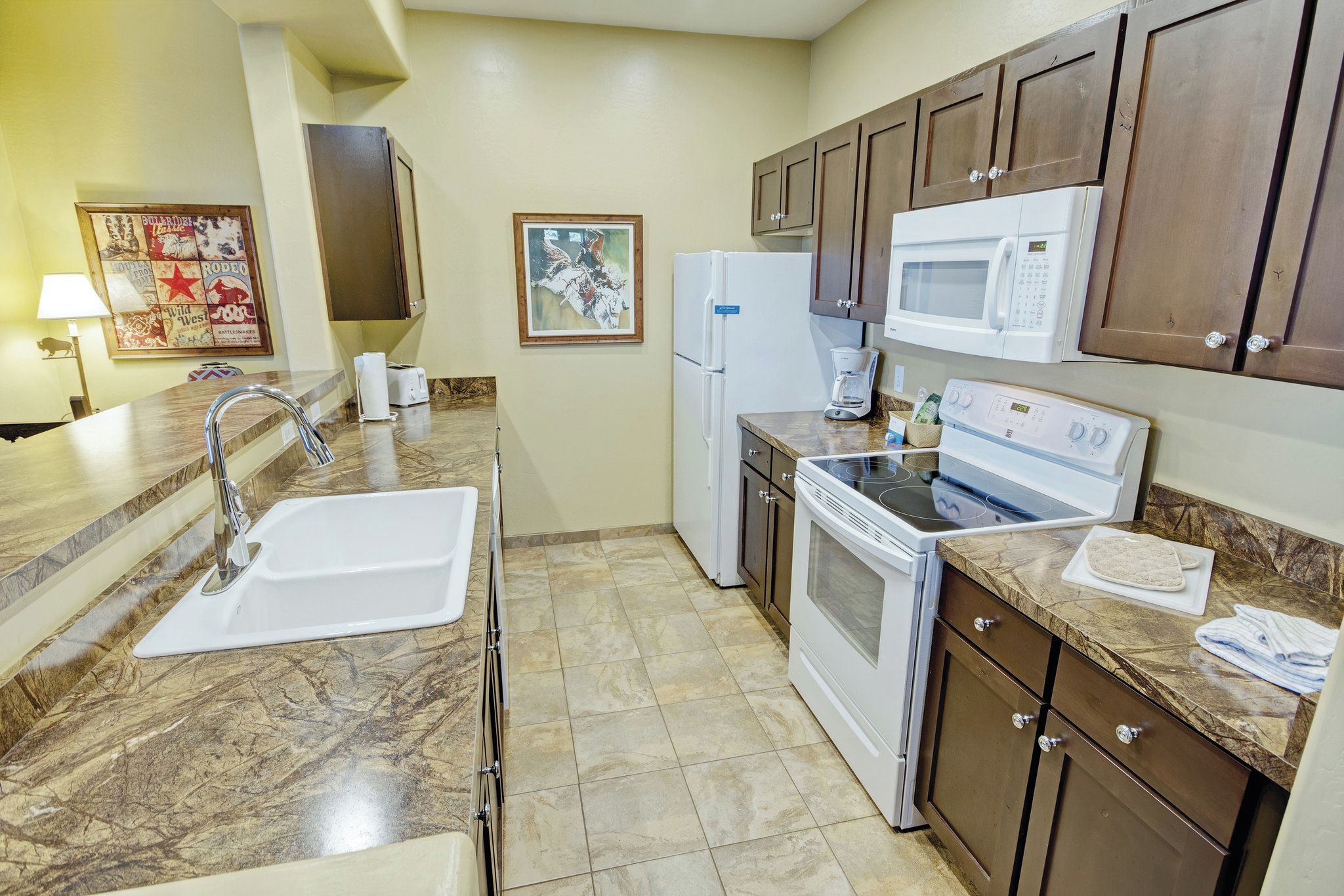 A kitchen with a sink, stove, microwave, and cabinets.