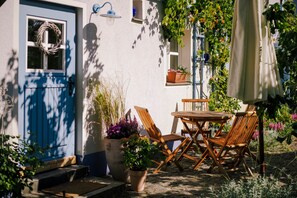 Eine Terrasse mit Tisch und Stühlen, einem Blumentopf und einer Tür mit einem Kranz.