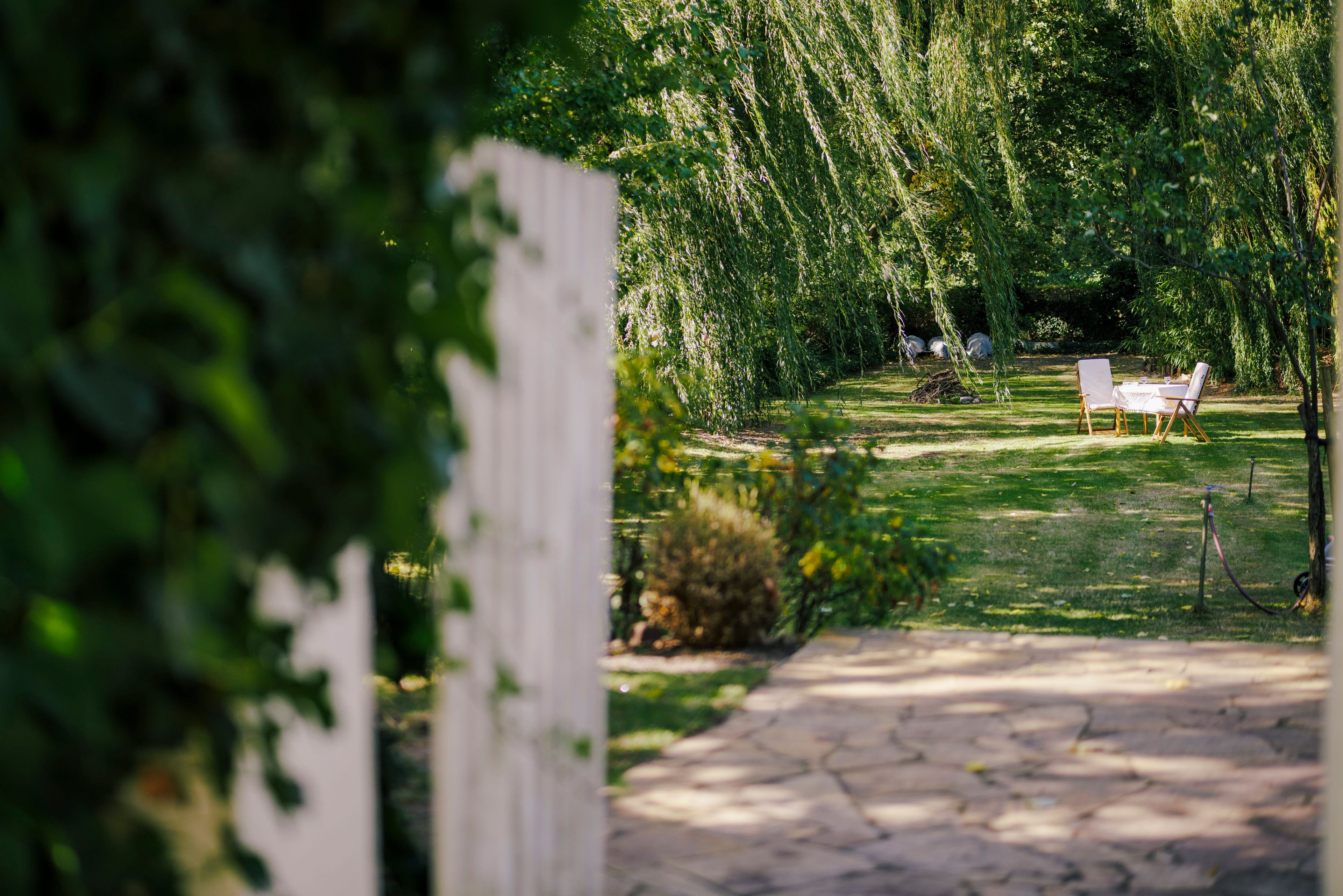 Ein Gartenweg führt zu einer Sitzgelegenheit mit Tisch und Stühlen.