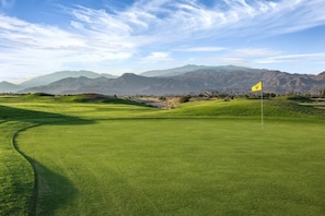 A golf course with a flag, rolling hills, and mountains in the background. - Palm Springs | Easy Access Studio Stay | Pool + Spa (Cathedral City)