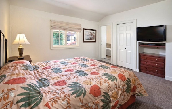 A bedroom with a bed, a TV, a dresser, a lamp, and a window with a view of houses. - Clear Lake | Cozy Lake Retreat | Pool + Lake (Nice)
