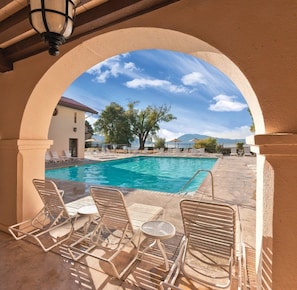 A pool area with a clear view of the pool, lounge chairs, and a table.