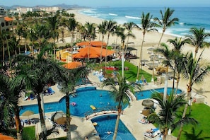 Un resort con piscina, playa y palmeras.