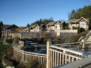 A residential area with multiple houses, a fenced deck, and a clear sky. - Deer Harbor | Relaxing Cottage Retreat | Pool + Marina (Deer Harbor)