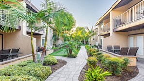 Un cortile con posti a sedere all'aperto, palme e un vialetto di giardino curato.
