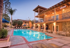 A hotel with a swimming pool, outdoor seating, and a balcony with a stone wall. - Anaheim | Romantic Disney Retreat | Pool + Parks (Anaheim)