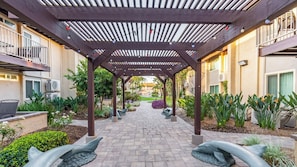 A covered outdoor area with a brick pathway, surrounded by greenery and plants. - Anaheim | Romantic Disney Retreat | Pool + Parks (Anaheim)