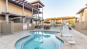 Piscina con tobogán, mobiliario exterior y una zona cubierta con escaleras.