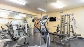 Een sportschool met diverse fitnessapparaten, waaronder loopbanden, hometrainers en krachtapparaten.