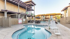 Piscina con tobogán, mobiliario exterior y una zona cubierta con escaleras.