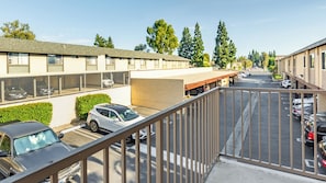 A parking lot with several cars, a building with multiple windows, and a fenced area. - Anaheim | Family Disney Retreat | Pool + Parks | 3BR Sleeps 8 (Anaheim)