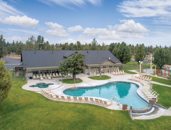 A large swimming pool with a deck area, surrounded by a covered patio and a grassy lawn. - Redmond | High Desert Comfort Escape | Pool + Trails (Redmond)