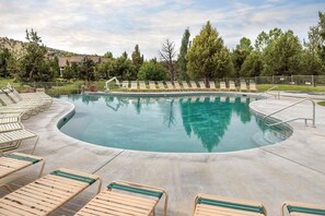 A swimming pool with lounge chairs and a metal fence.