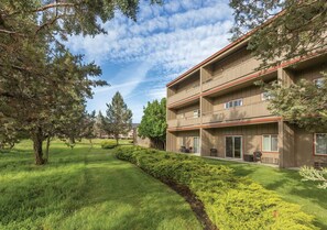 A multi-story building with balconies, surrounded by well-maintained lawns and trees.