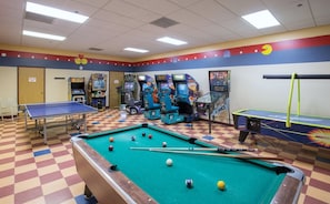 A recreational room with a pool table, billiards, and various arcade games.