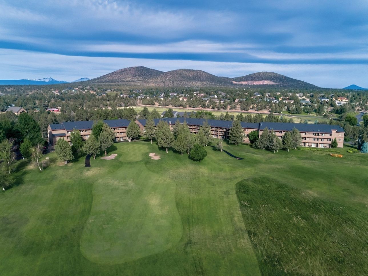 Luchtbeeld van een golfbaan met een groot complex op de achtergrond.