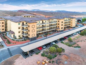 A multi-story hotel with a covered parking area and a view of the surrounding desert landscape. - St George | Elevated Red Rock Retreat | Pool + Hot Tub | 3BR Sleeps 6 (St. George)