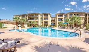 A hotel with a swimming pool, lounge chairs, and palm trees. - St George | Elevated Red Rock Retreat | Pool + Hot Tub | 3BR Sleeps 6 (St. George)
