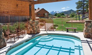 Ein Poolbereich mit einer Steinmauer, einer Holzterrasse und Stühlen.