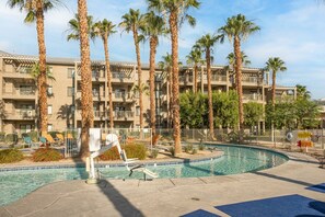 A hotel with a swimming pool surrounded by palm trees and lounge chairs. - Indio | Desert Couples Getaway | Pool & Lazy River (Indio)