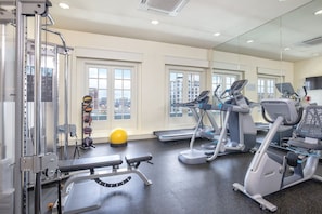 Ein Fitnessraum mit Trainingsgeräten, einer Bank und einem gelben Trainingsball.