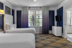 Une chambre d’hôtel avec deux lits, une commode, un téléviseur et une fenêtre avec des rideaux.