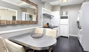 Une cuisine moderne dotée d’un coin repas, comprenant une table avec des chaises, un îlot de cuisine et un réfrigérateur.