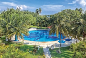 A large outdoor swimming pool surrounded by palm trees and greenery. - Isla Mujeres | Romantic Beach Retreat | Pool + Beach (Isla Mujeres)