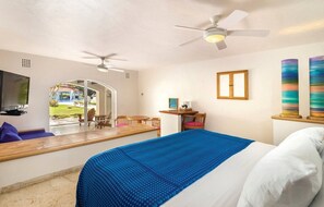Camera d'albergo con un letto, ventilatore a soffitto, televisore e vista sulla zona esterna.