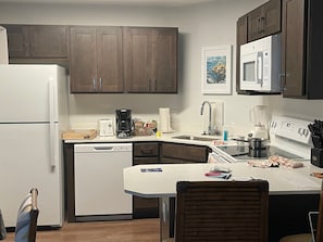 Eine kompakte Küche mit Kühlschrank, Mikrowelle, Kaffeemaschine und Geschirrspüler.