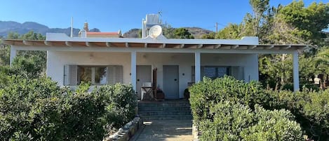 A two-story house with a covered porch, a satellite dish, and a stone pathway leading to the entrance.