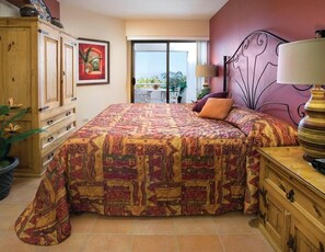 Een slaapkamer met een groot bed, een houten dressoir, een nachtkastje, een lamp, een schilderij en uitzicht op de omgeving.